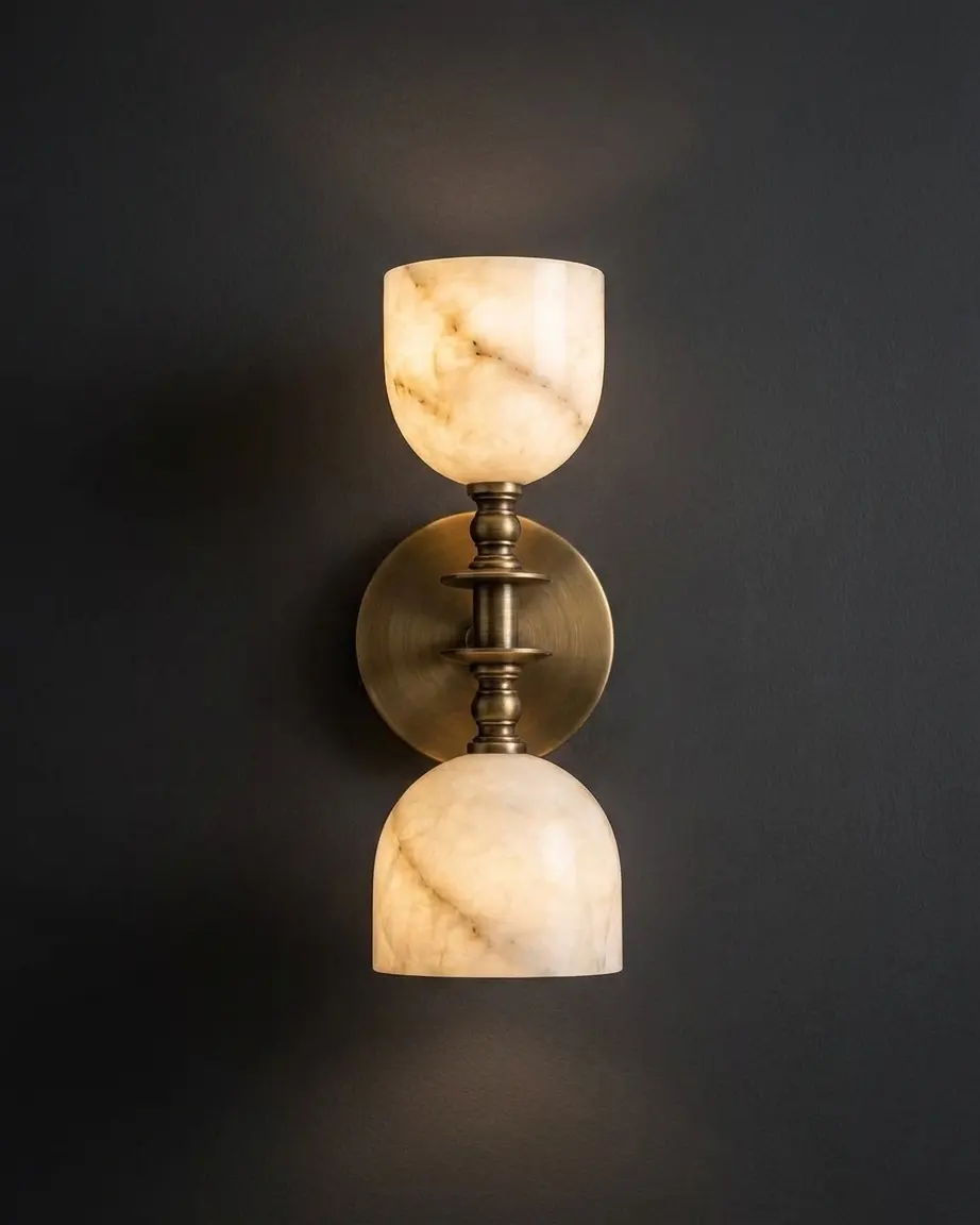 Double-goblet alabaster wall sconce glowing against a dark charcoal wall