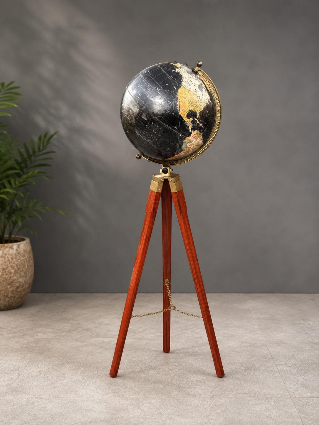 Black world globe with a graduated brass meridian ring on a rosewood-toned wooden tripod stand with brass fittings and chain
