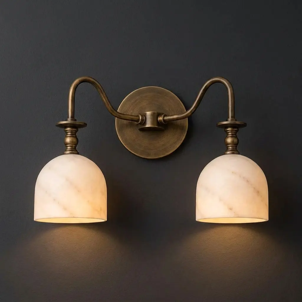 Twin-arm alabaster bell-shade wall sconce glowing against a dark charcoal wall